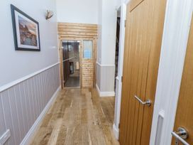 A hallway with wooden flooring and doors at Jackdaw in Bamburgh