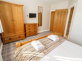 A bedroom with a wardrobe, chest of drawers, and bed at Jackdaw in Bamburgh