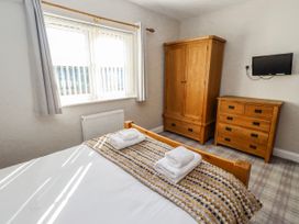 A bedroom with a bed and a wardrobe at Jackdaw in Bamburgh