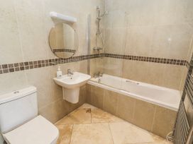 A bathroom featuring a toilet, sink, mirror, shower, and bathtub at Jackdaw in Bamburgh
