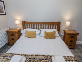 A bedroom with a wooden bed and nightstands at Jackdaw in Bamburgh