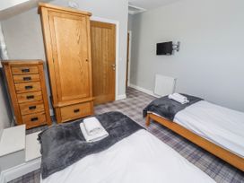 A bedroom with two beds and a wardrobe at Jackdaw in Bamburgh