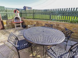 A garden with a table and chairs near a barbecue at Jackdaw in Bamburgh