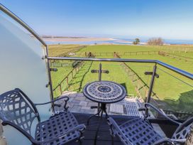 A balcony with a table and chairs overlooking grass fields at Jackdaw in Bamburgh