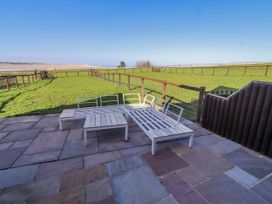 An outdoor patio area with lounge chairs overlooking a grassy field at Jackdaw in Bamburgh