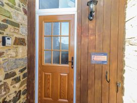 An entrance with a wooden door and stone wall at Heather House in Bamburgh