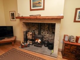 A fireplace with a wood stove and television in Riverside Cottage in Warkworth