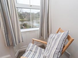 A sitting room with a chair and window view at Riverside Cottage in Warkworth