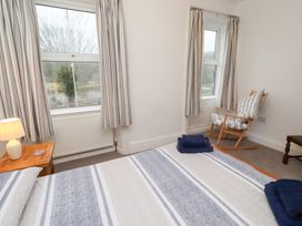 A bedroom with a bed, a rocking chair, and a window at Riverside Cottage in Warkworth