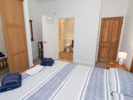 A bedroom with a bed and a bathroom doorway at Riverside Cottage in Warkworth