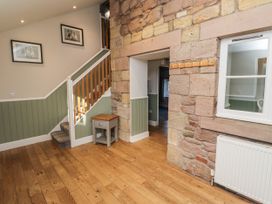 A hallway with a staircase and side table at Millstone in Lucker