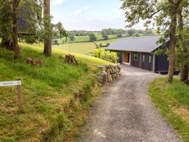 A gravel path leading to a house with trees on the side at Bwncath in Garthmyl