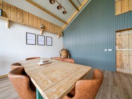 A dining room with a wooden table and leather chairs at Bwncath in Garthmyl