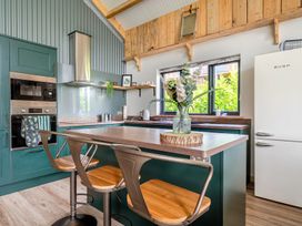 A kitchen with a refrigerator and bar stools at Bwncath in Garthmyl