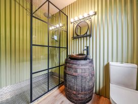 A bathroom with a shower, sink in a barrel and toilet at Bwncath in Garthmyl