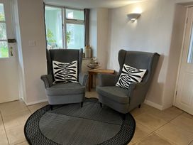 Two grey armchairs with black and white patterned cushions on a round black and grey rug in a tiled room at Fisherman's Cottage in Southwell