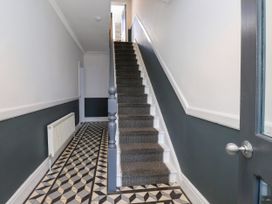 A hallway with a staircase and patterned flooring at Ty Haul in Rhosneigr