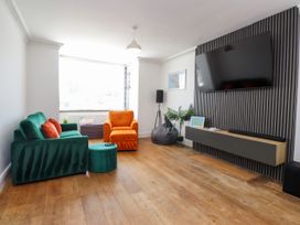 A living room with a green sofa and orange armchair at Ty Haul in Rhosneigr