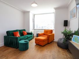 A living room with a green sofa and an orange armchair at Ty Haul in Rhosneigr