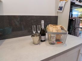 A kitchen countertop with champagne, glasses, and a basket at Ty Haul Rhosneigr