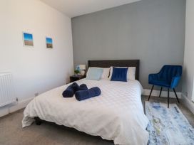 A bedroom with a bed and a blue chair at Ty Haul in Rhosneigr