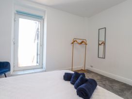 A bedroom with a door, hangers, towels, and a mirror at Ty Haul in Rhosneigr
