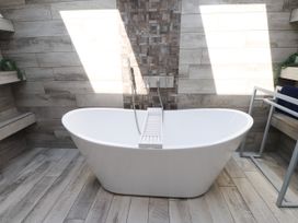 A bathroom featuring a bathtub and wall tiles at Ty Haul in Rhosneigr