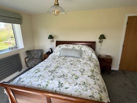 A bedroom with a bed and armchair at How Hill Farm Cottage in Greystoke