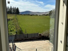 View of grass field and mountains from a window at How Hill Farm Cottage in Greystoke