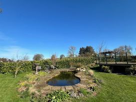 A garden with a pond and flower bed at How Hill Farm Cottage in Greystoke