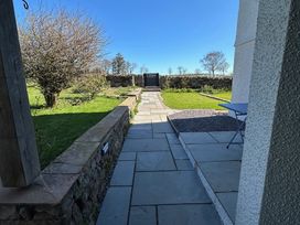 A garden view with a pathway, stone wall, and gate at How Hill Farm Cottage in Greystoke