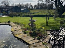 A garden with a pond and fountain at How Hill Farm Cottage Greystoke