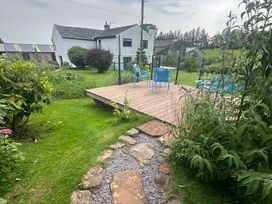 A garden with a house and deck in the background at How Hill Farm Cottage in Greystoke