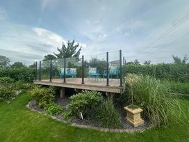 A garden deck with chairs and plants at How Hill Farm Cottage Greystoke