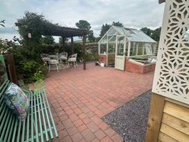 A garden with a patio area and greenhouse at How Hill Farm Cottage Greystoke