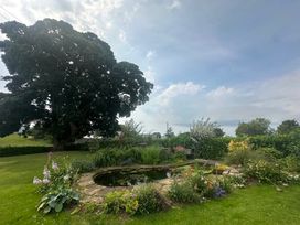 A garden with a pond and flowers at How Hill Farm Cottage Greystoke