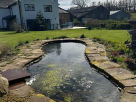 A pond with a stone pathway and grass at How Hill Farm Cottage in Greystoke