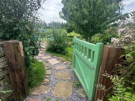 A garden with a green gate and stone pathway at How Hill Farm Cottage Greystoke