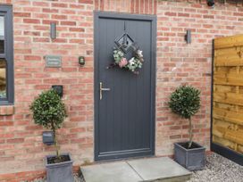 Front door with floral wreath and potted plants on either side at Bracken Cottage in Pocklington