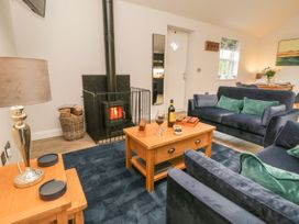 A living room with blue sofas a wooden coffee table a lamp and a fireplace at Bracken Cottage in Pocklington