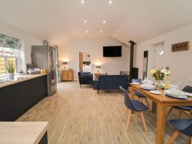 An open plan kitchen and living area with a dining table set and blue chairs at Bracken Cottage in Pocklington