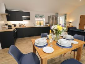 A kitchen and dining area with a wooden table set for four with plates glasses and flowers at Bracken Cottage in Pocklington