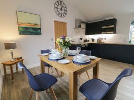 A kitchen and dining area with a wooden table set for four with blue chairs and a flower centerpiece at Bracken Cottage in Pocklington