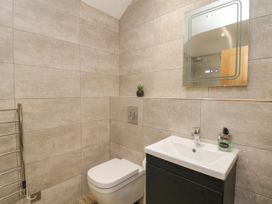 A bathroom with a toilet a sink with a soap dispenser a mirror and a towel warmer at Bracken Cottage in Pocklington