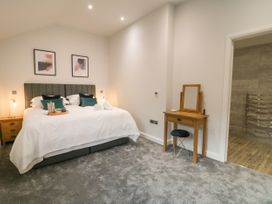 A bedroom with a large bed pillows bedside tables lamps a wooden dressing table with mirror and a stool at Bracken Cottage in Pocklington
