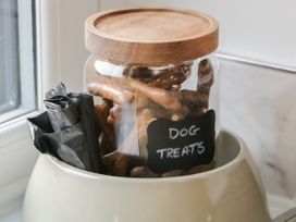 A jar of dog treats and black bags inside a white pet bowl by a window at Bracken Cottage in Pocklington