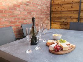 A patio table with a cheese platter grapes crackers a bowl of crisps and four empty wine glasses with a bottle of prosecco at Bracken Cottage in Pocklington
