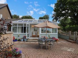 A garden with a table and chairs under an umbrella at Rainbow View in Churchstanton near Churchinford