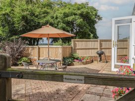 A garden with a seating area and umbrella at Rainbow View Churchstanton near Churchinford