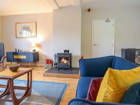 A living room with a blue sofa with cushions a coffee table a wood burning stove and a sideboard at The Wardens House in Tregynon near Newtown